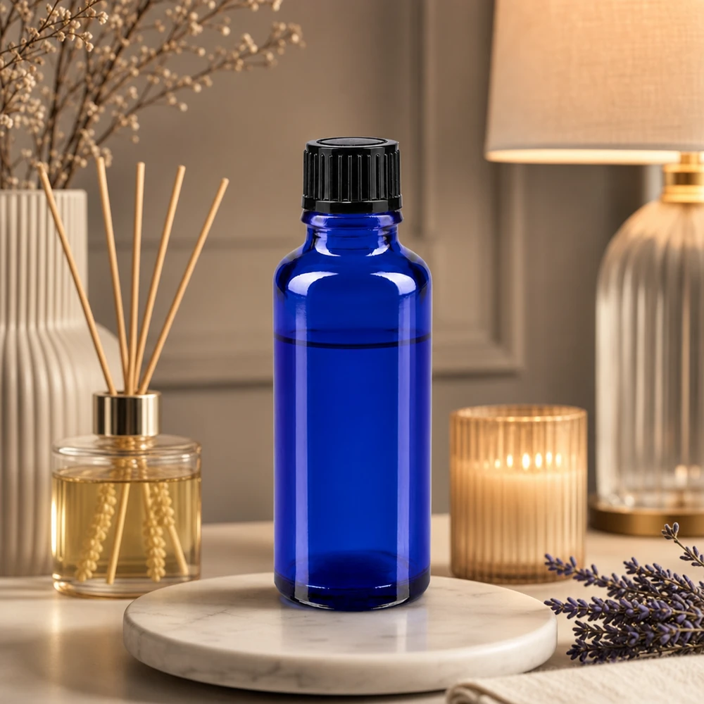 Blå 30 ml apotekerflaske med sort dråbepropp ved siden af lavendel og en duftdiffusor