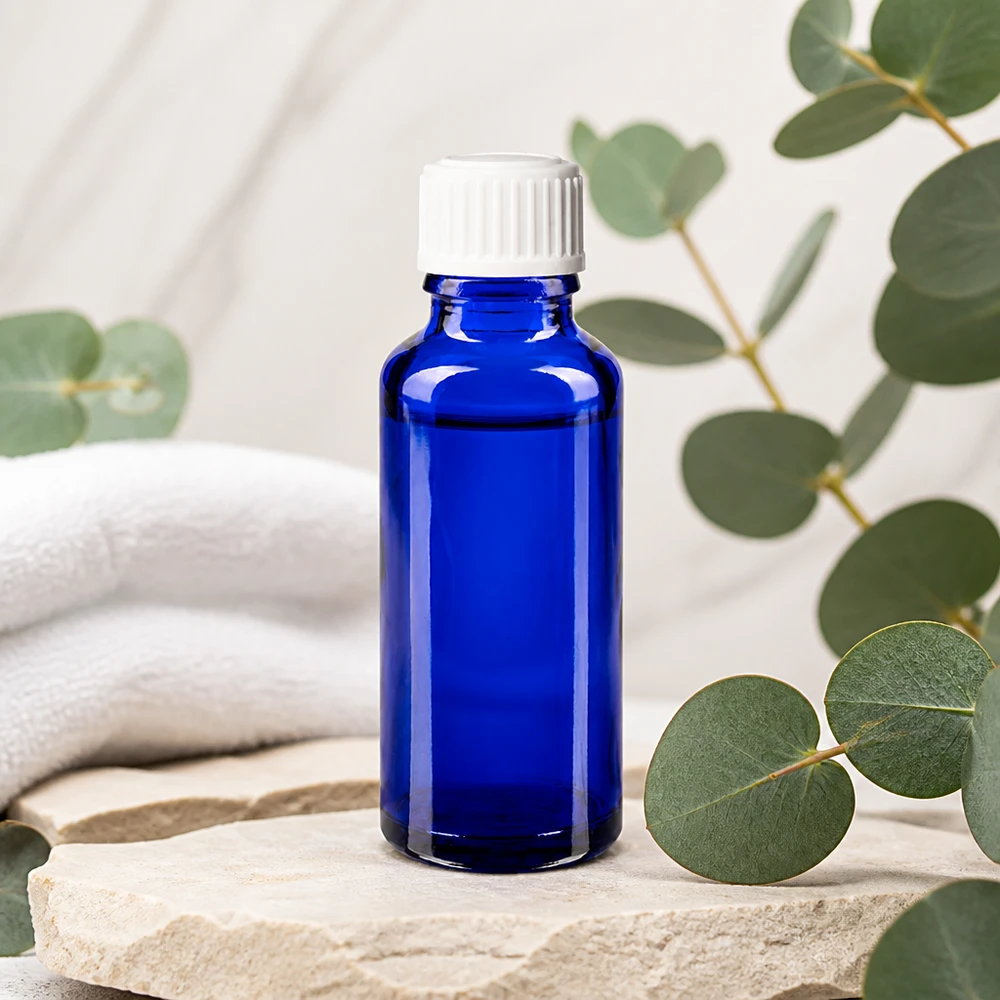 Apoteksflaske blå 30 ml skruelåg hvid pc Koboltblå 30 ml apotekerflaske med hvidt dråbehoved på natursten med eukalyptus