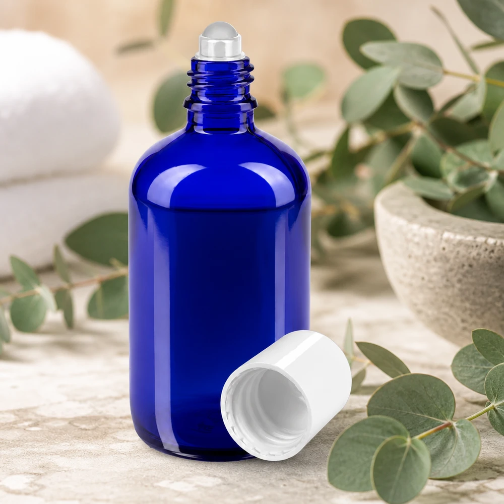 Apoteksflaske blå 100 ml roll-on-hætte hvid 100 ml roll-on-flaske i blåt med stålkugle og hvidt låg mellem eukalyptusgrene