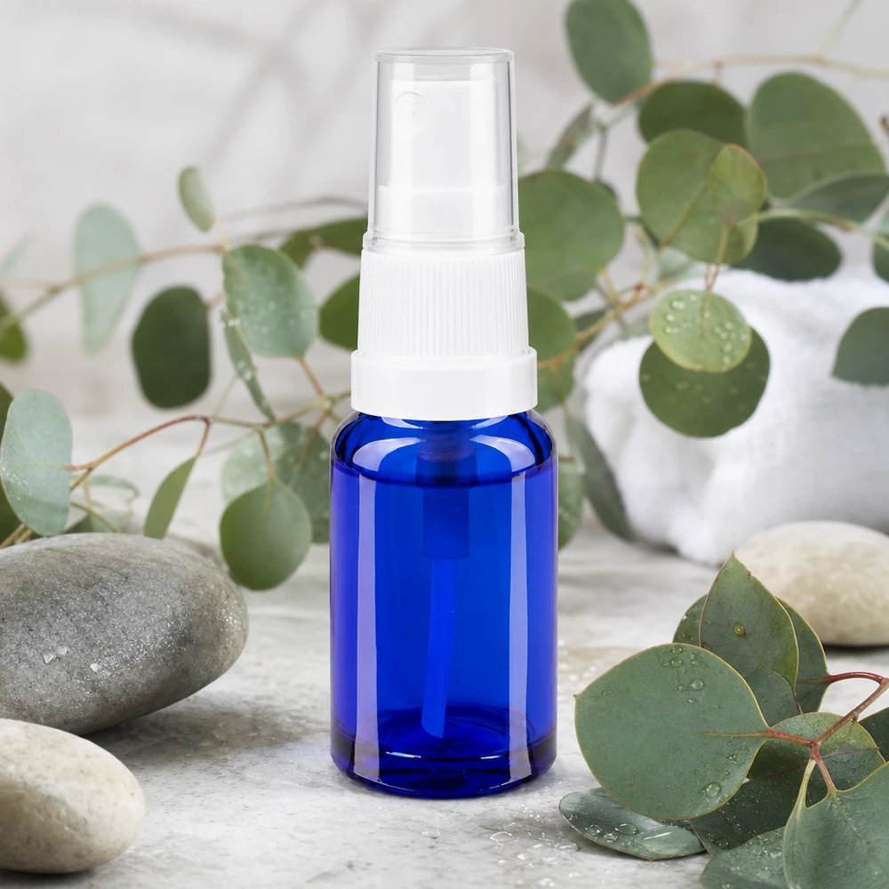 10 ml flakon af koboltblåt apotekerglas med hvid forstøverhoved omgivet af eukalyptusgrene