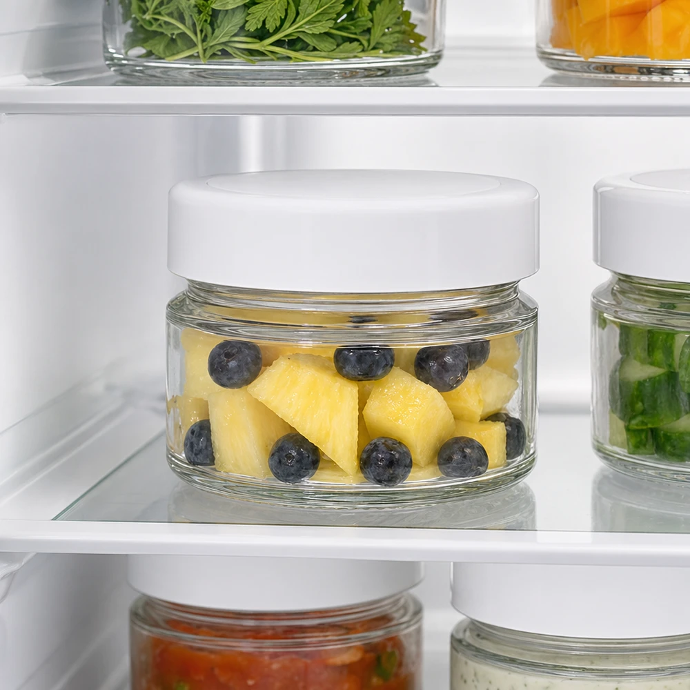 80 ml rund krukke med BasicSeal-låg hvid dyb UNiTWIST 80 ml rund krukke i køleskabet med ananas og blåbær viser BasicSeal-lågets optimale egenskaber til at holde på friskheden