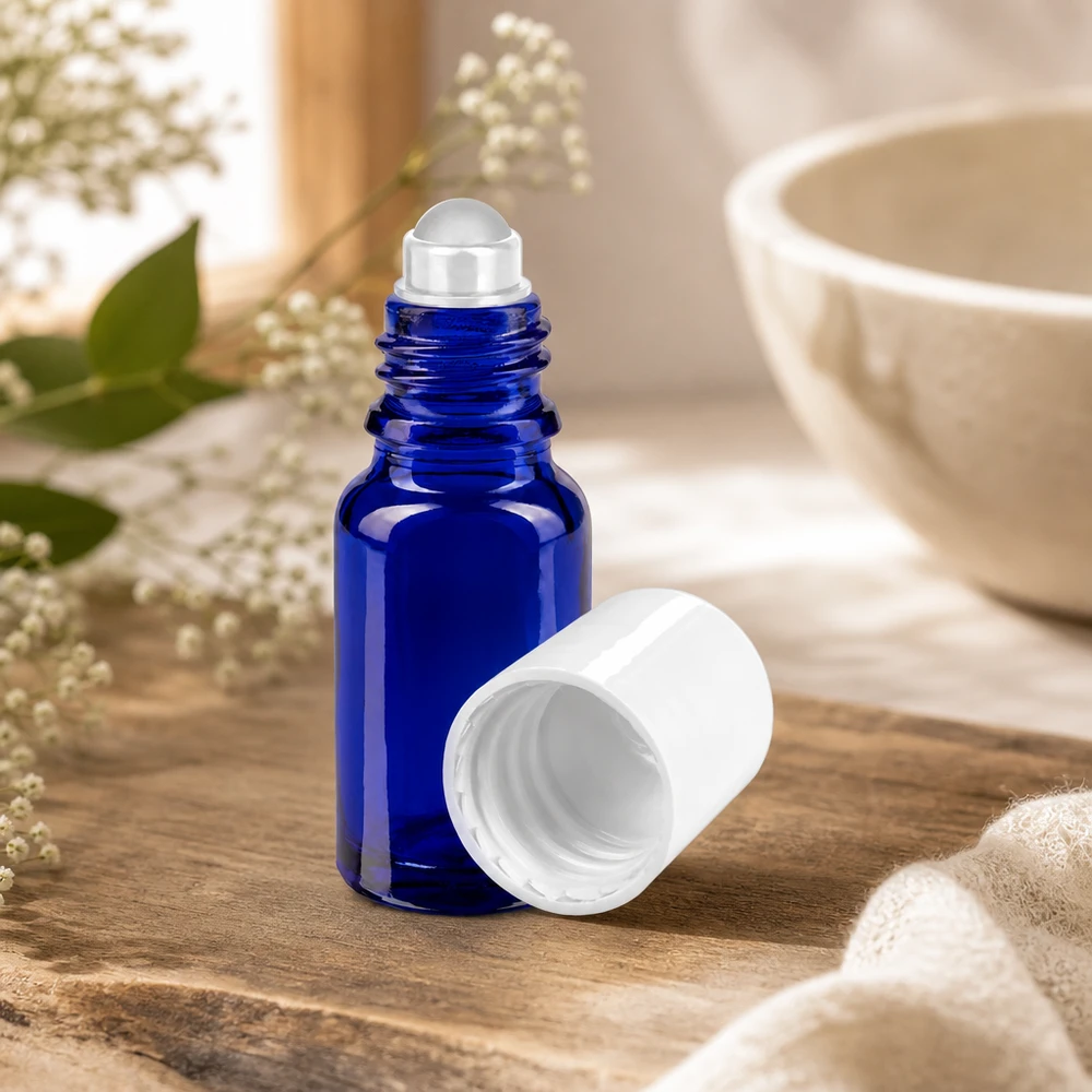 Apoteksflaske blå 10 ml roll-on-hætte hvid Åben koboltblå 10 ml roll-on-glasflaske med afmonteret hvidt låg på en træbaggrund