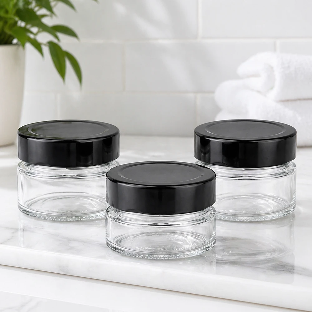 80 ml rund krukke + BasicSeal-låg sort dyb UNiTWIST Tre runde krukker på 80 ml med sorte BasicSeal-låg UNiTWIST på hvid marmorplade Bathroom ambience empty