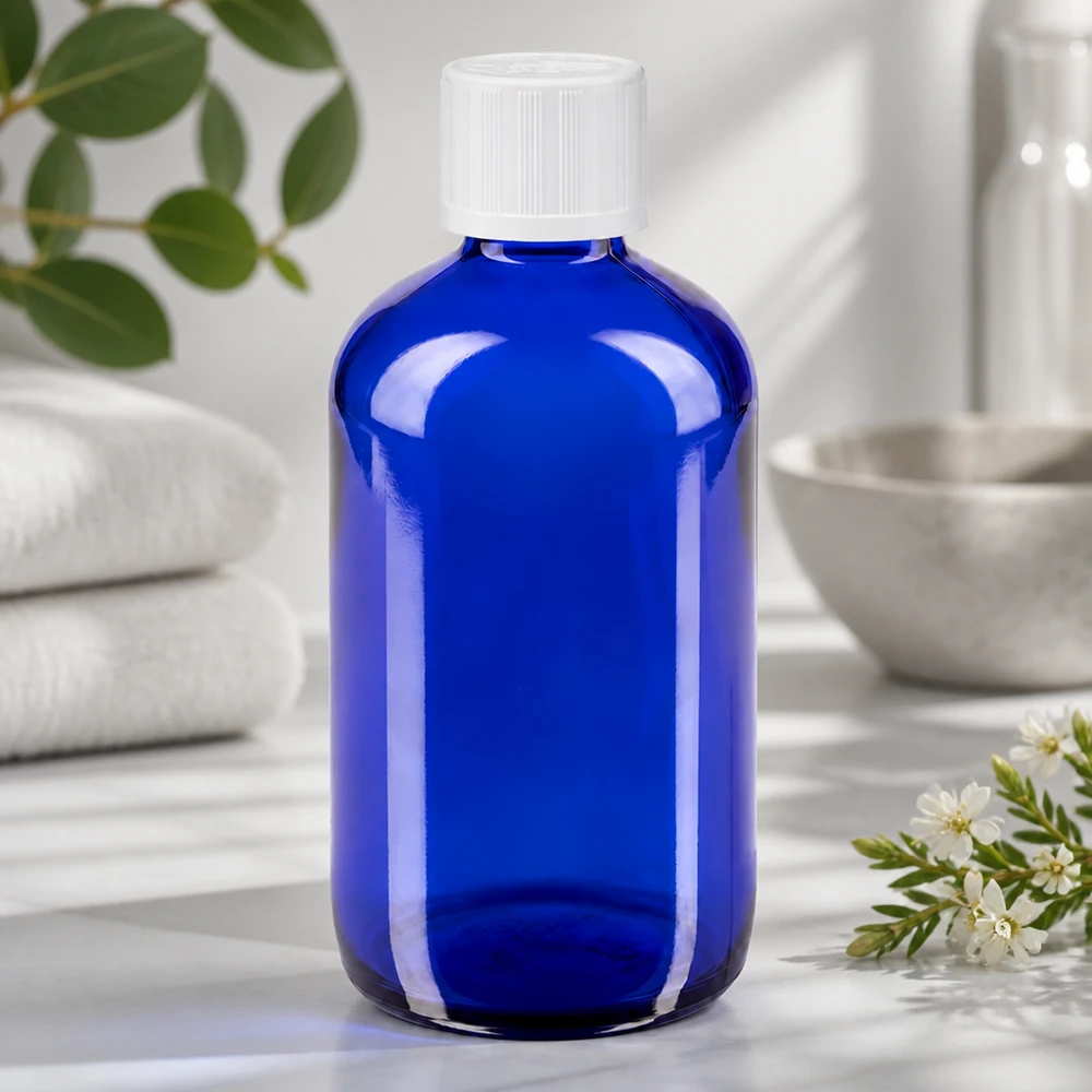 Gennemsigtig blå glasflaske på 100 ml med hvid børnesikret låg og dråbeindsats på 1,2 mm