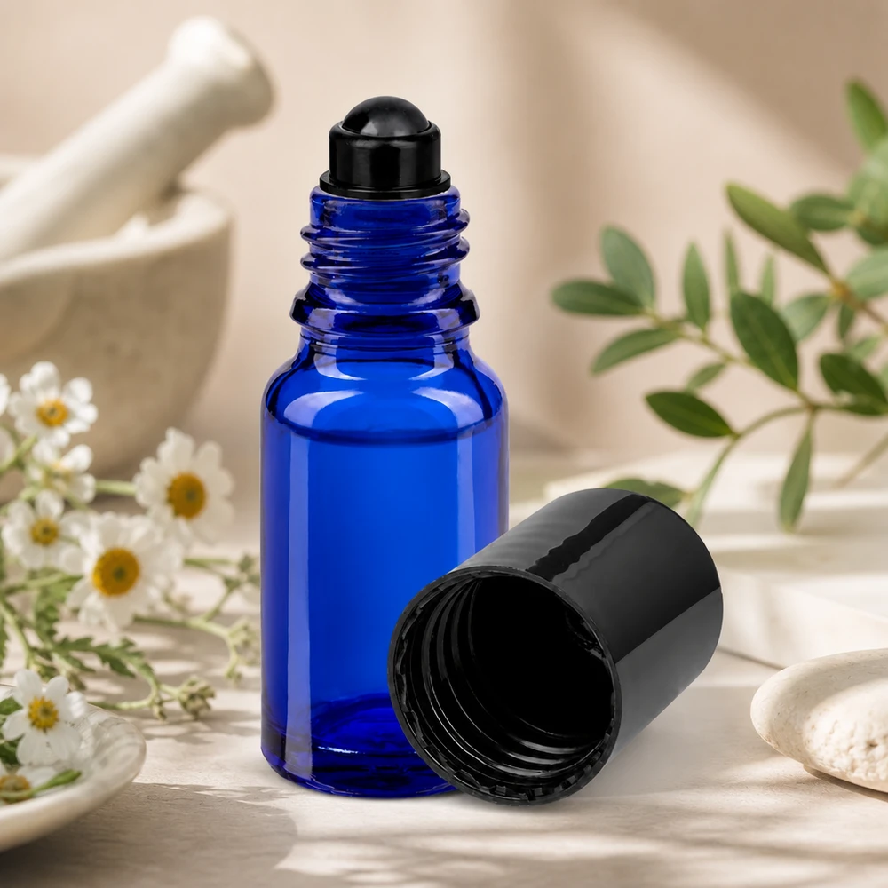 Apoteksflaske blå 10 ml roll-on-hætte sort Blå 10 ml roll-on-flaske STD med sort låg ved siden af morterurter og kamilleblomster