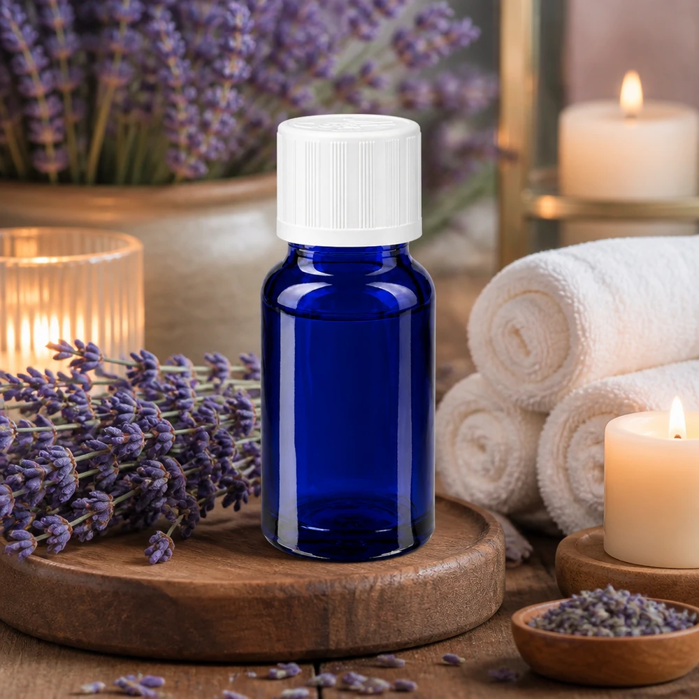 Blå 10 ml glasflaske med hvid børnesikret lukning mellem lavendelblomster og stearinlys