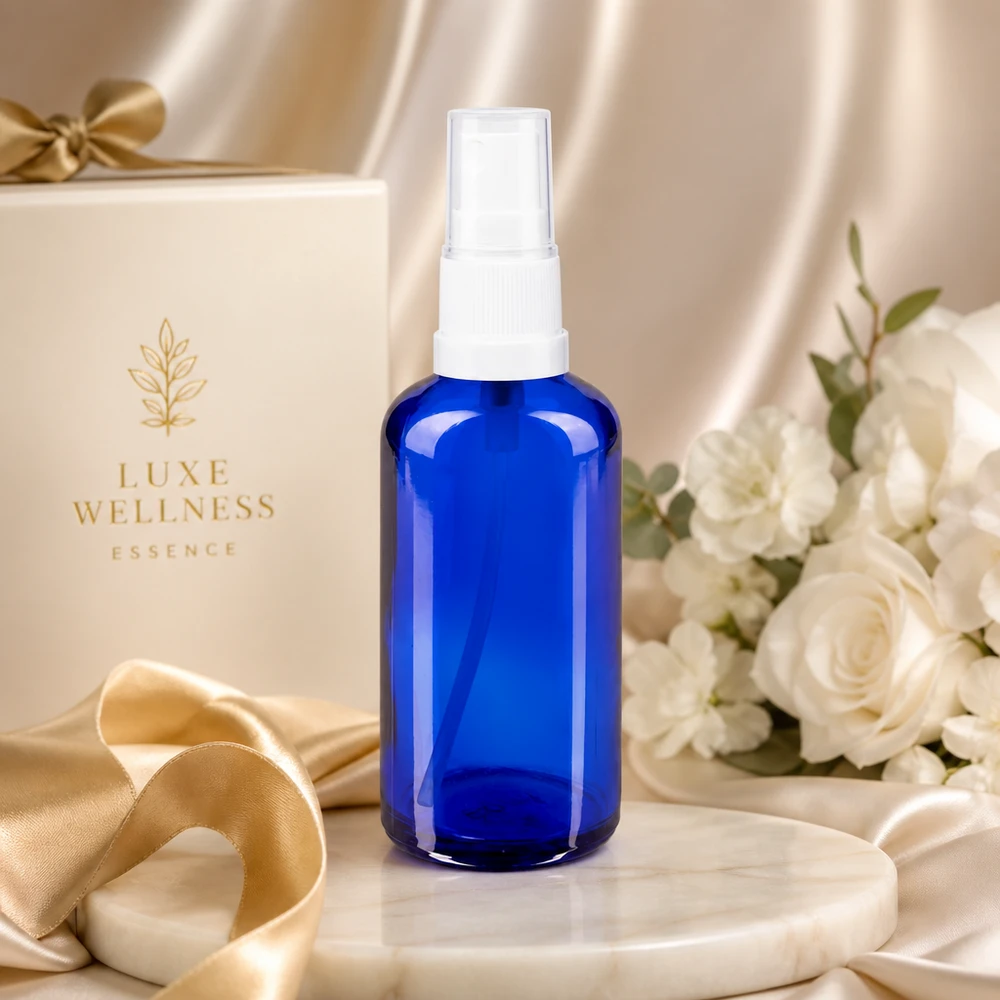Apoteksflaske blå 50 ml spraytop hvid Koboltblå 50 ml glasflaske med hvidt sprøjtehoved foran en elegant gaveæske i baggrunden