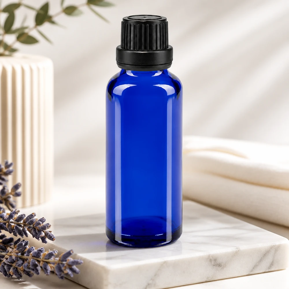 Blå 30 ml ApoGlas-dråbeflaske med 2 mm indsats og sort låg ved siden af lavendel på marmor