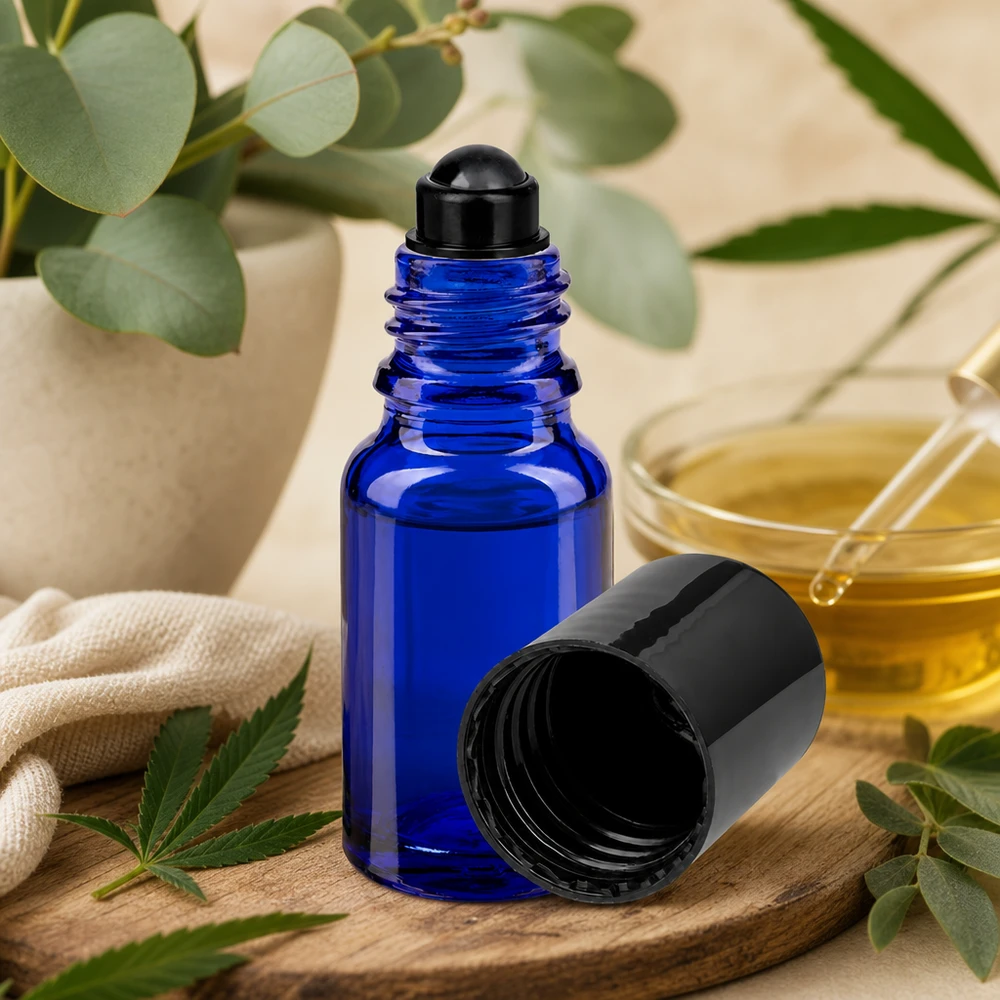 Blå 10 ml ApoGlas-roll-on-flaske med sort låg på et træbræt ved siden af et cannabisblad og et eukalyptusblad