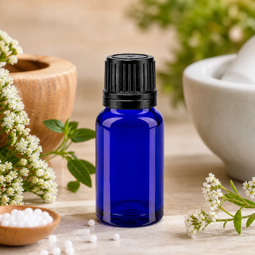 Blå 10 ml apotekerflaske med sort OV-lukning mellem hvide blomster og en morter