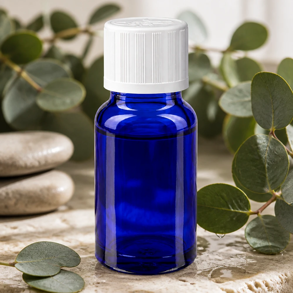 Blå 10 ml apotekerflaske med hvid børnesikret låg mellem eukalyptusgrene
