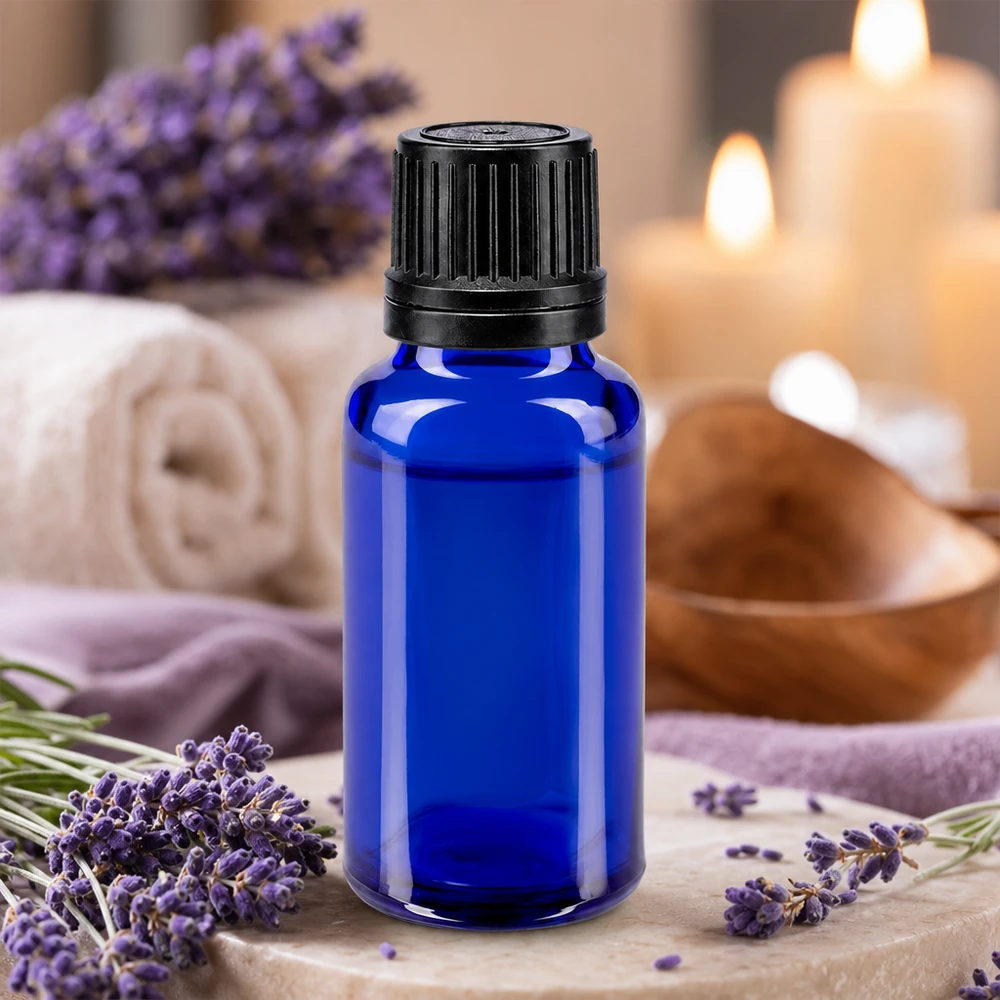 Blå 20 ml glasflaske med sort dråbepropp omgivet af lavendelblomster og stearinlys
