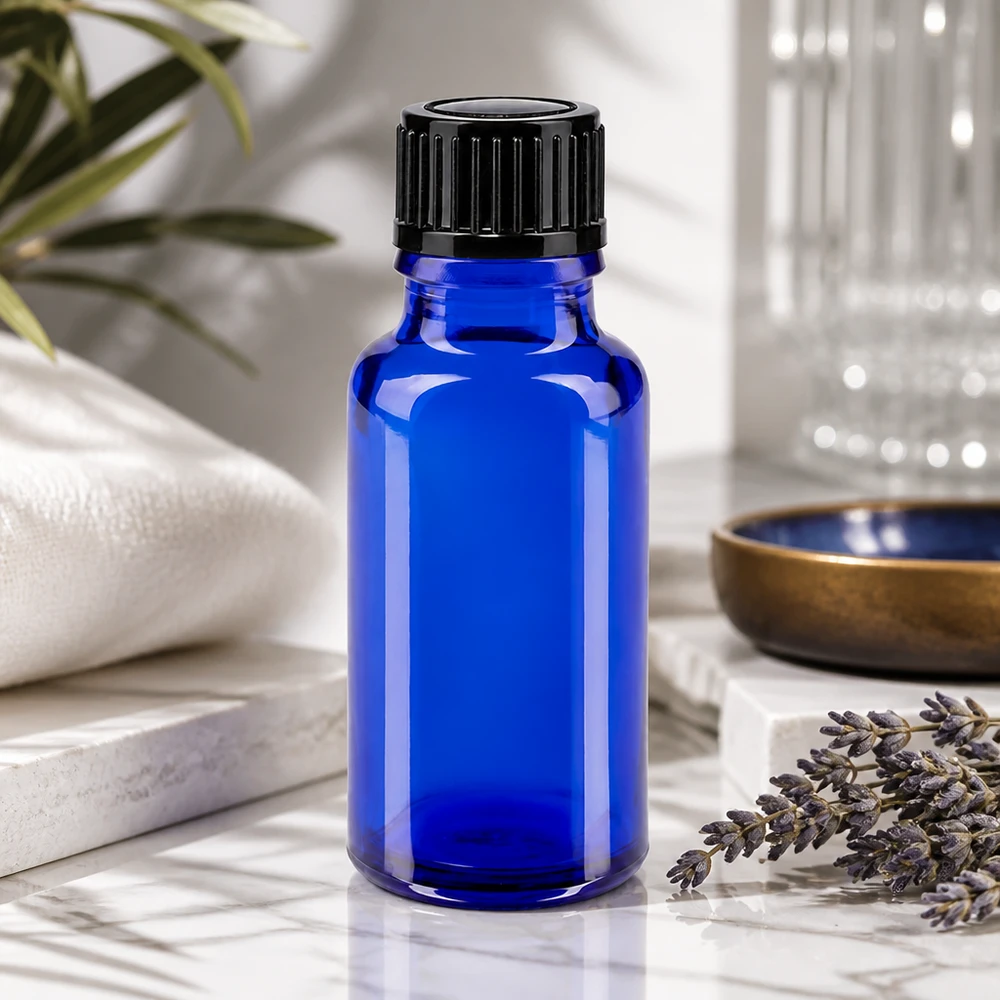 Apoteksflaske blå 20ml skruelåg sort pc 20 ml blå apotekerflaske med sort skruelåg ved siden af lavendelgrene på marmor