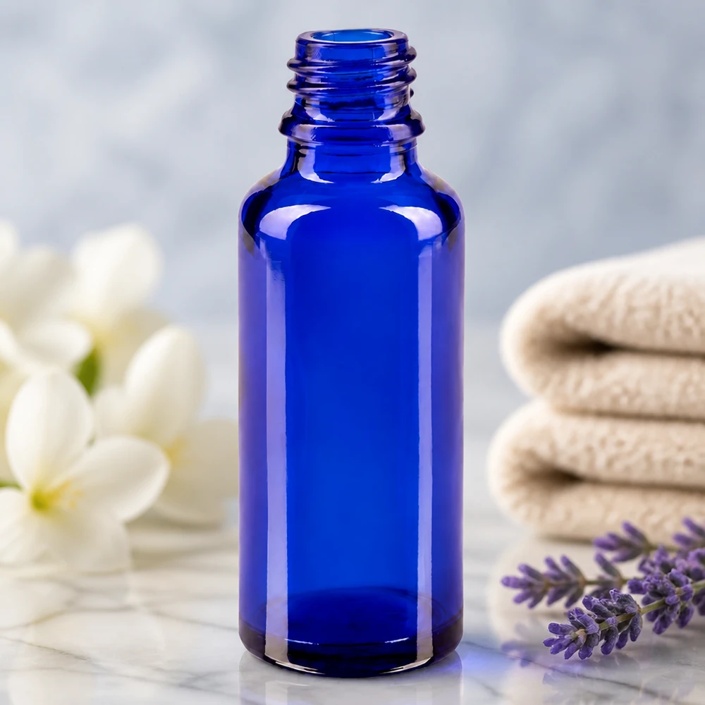 Tom 30 ml ApoGlas-apotekflaske i kongeblå ved siden af en lavendelgren og hvide blomster