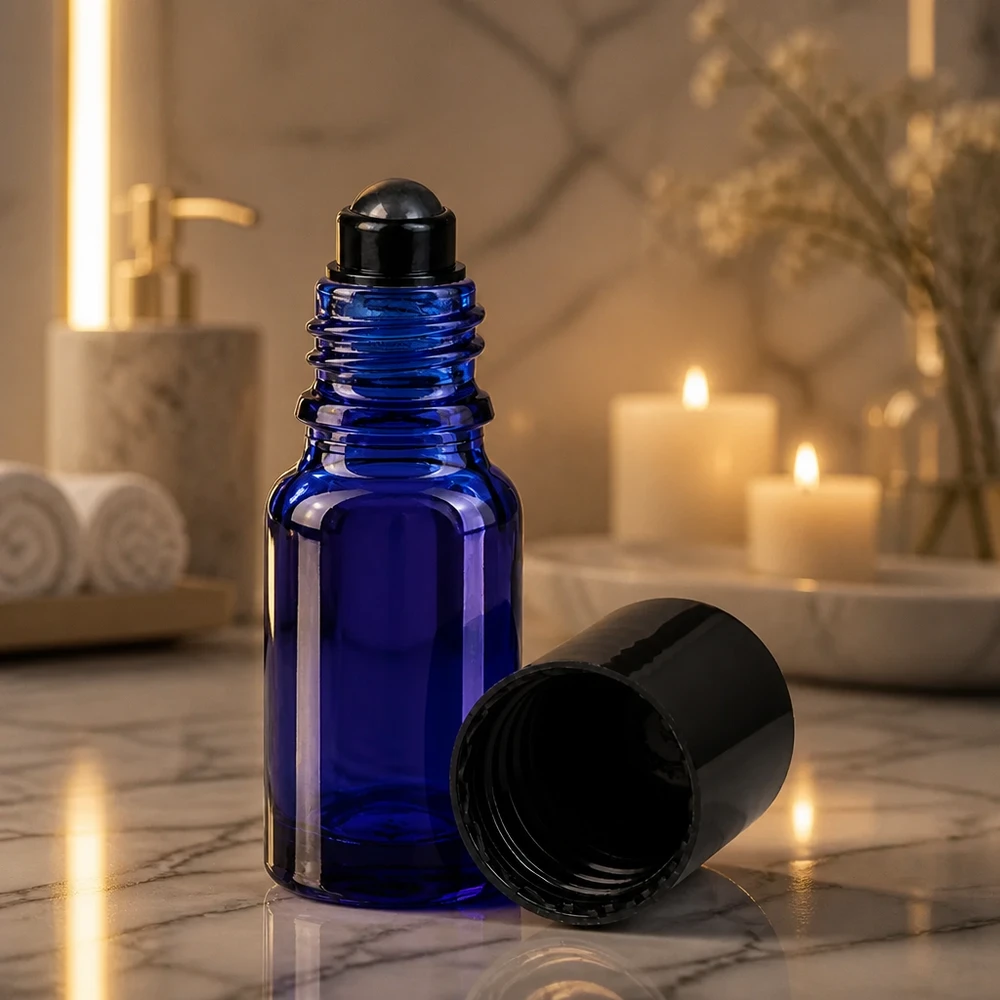 Apoteksflaske blå 10 ml roll-on-hætte sort Koboltblå 10 ml roll-on-flaske med sort rullekugle i stemningsfuldt stearinlys på marmor