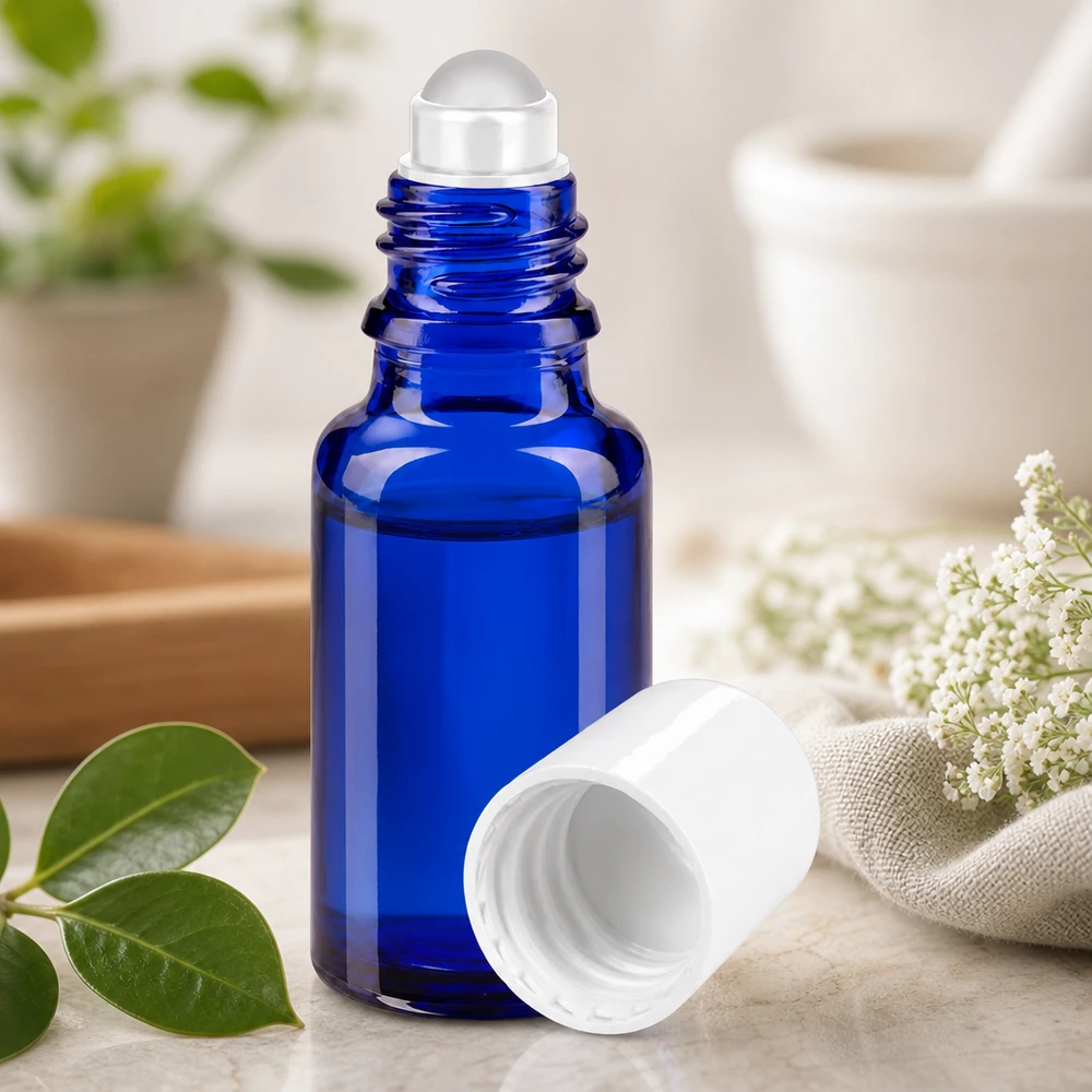Apoteksflaske blå 20 ml roll-on-hætte hvid Blå 20 ml apotekerflaske med gennemsigtig rullekugle ved siden af hvide blomster og grønne blade