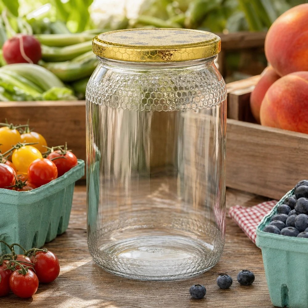 1260 g honningglas med låg med honningkagemønster BasicSeal UNiTWIST 900 ml honningkrukke tom med gyldent honningkagelåg mellem frisk frugt og grøntsager på køkkenbord af træ
