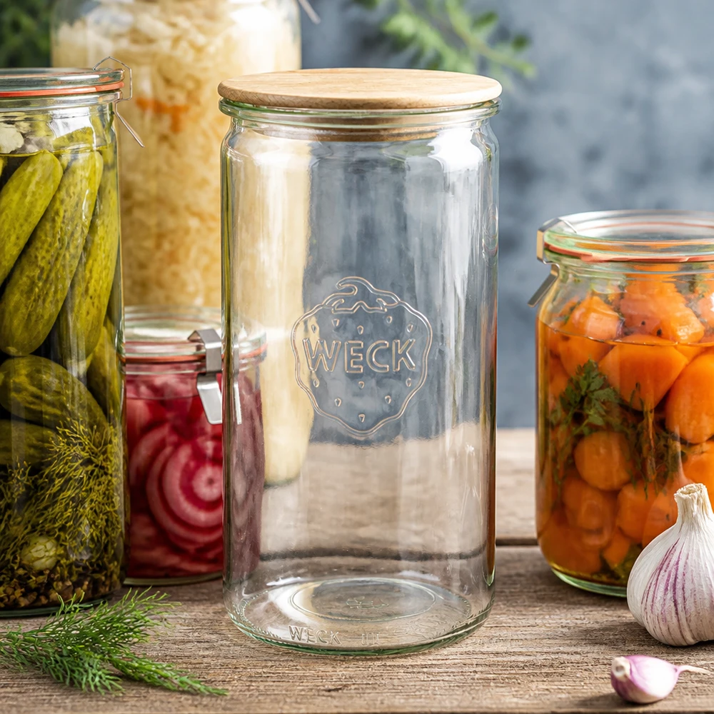 1590 ml cylinderglas WECK RR100 med trælåg WECK Zylinderglas 1590ml RR100 mit Holzdeckel zwischen Einmachgläsern mit Gurken Karotten und Sauerkraut auf Holztisch