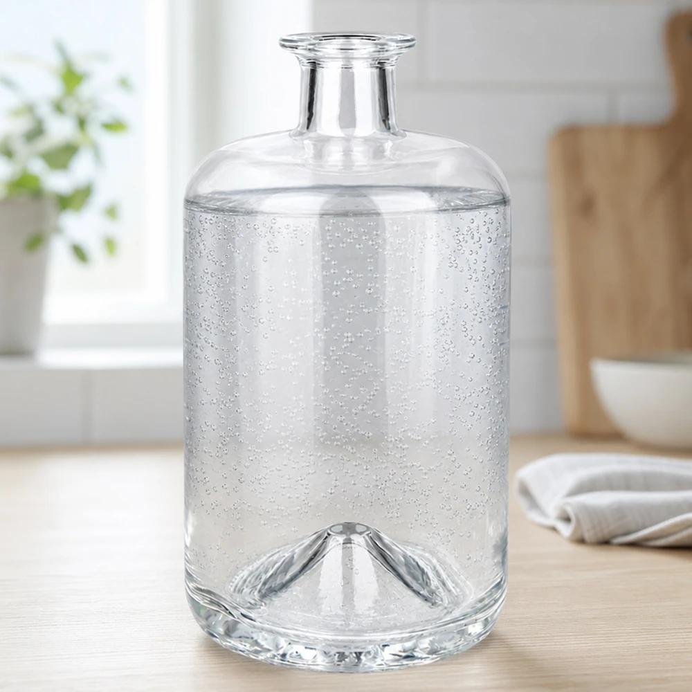 700 ml apoteksflaske »Sofia« uden lukning UNiTWIST® 700 ml Sofia-glasflaske fyldt med danskvand viser kuldioxidbobler i et lyst køkkenmiljø