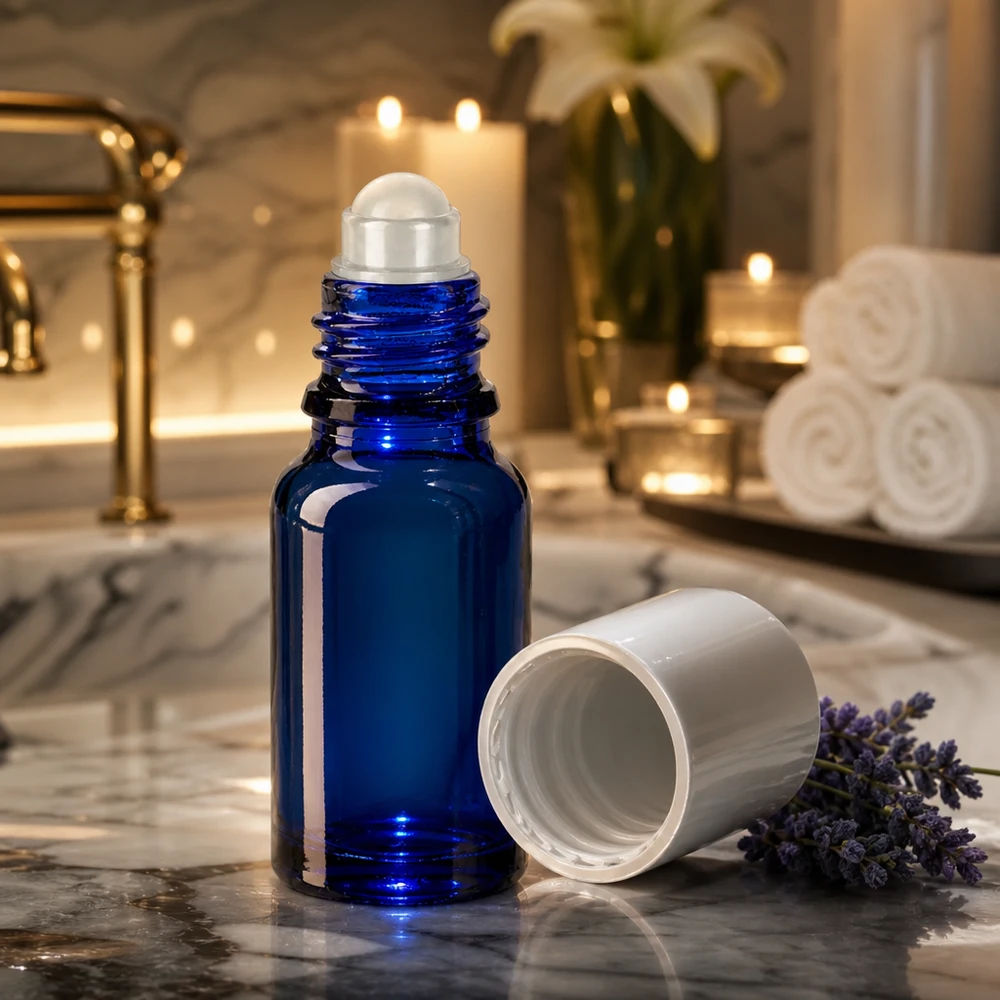 Koboltblå 10 ml roll-on-flaske med rulleapplikator på marmor ved siden af lavendelblomster