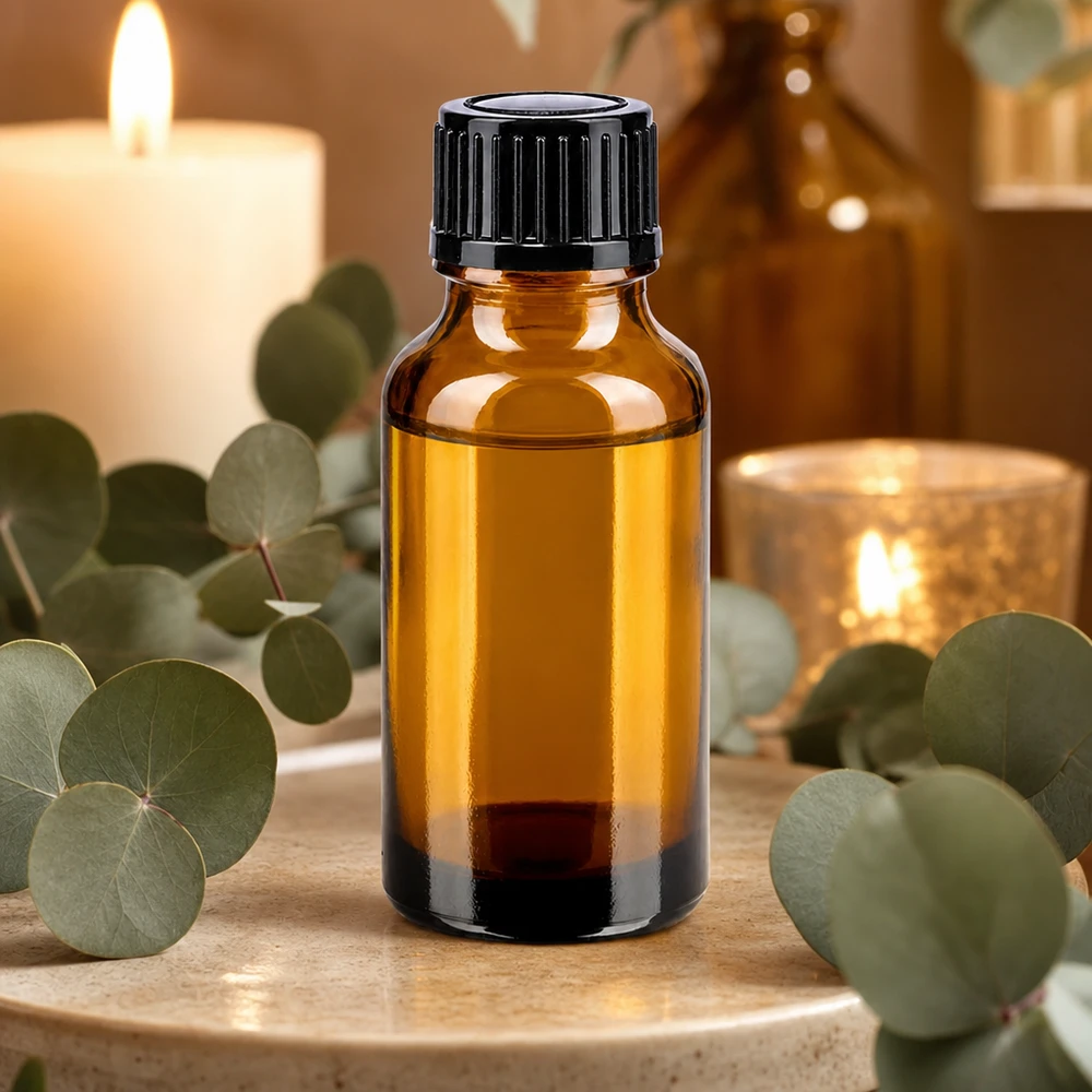 Brun glasflaske på 20 ml med sort skruelåg mellem eukalyptusgrene og stearinlys