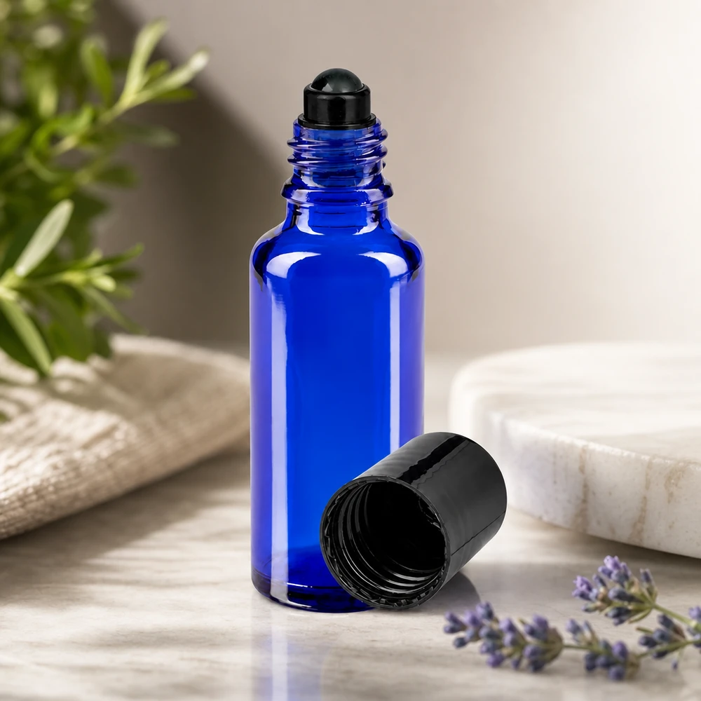 Koboltblå 30 ml roll-on-glasflaske med sort låg ved siden af lavendel og en rosmarinkvist