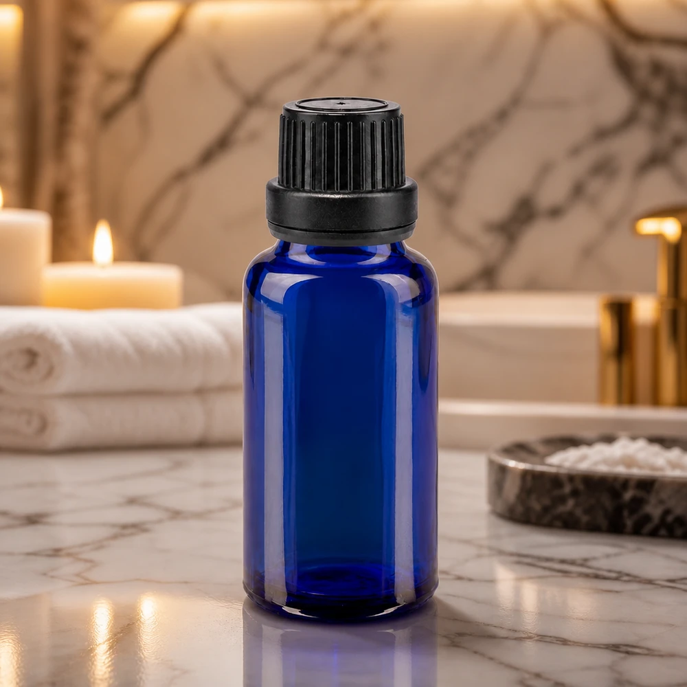 Koboltblåt apotekerglas på 20 ml med sort OV-låg på marmor i wellness-badeværelset