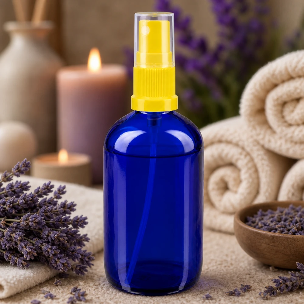 Apotekerflaske blå 100 ml spraytilbehør gul Lille blå glasflaske på 100 ml med gul sprøjtehoved omgivet af lavendel og stearinlys