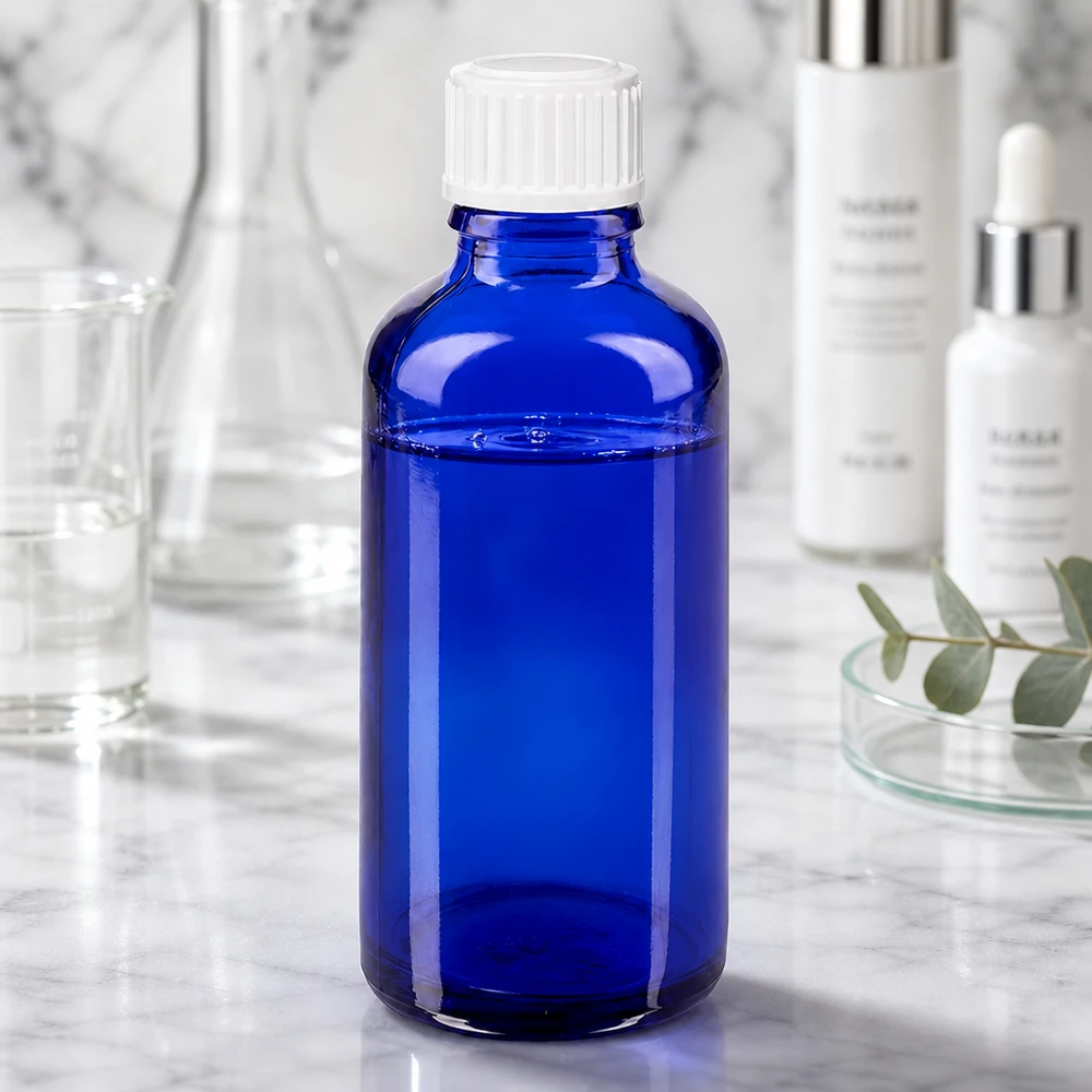 Blå 50 ml ApoGlas-dråbeflaske med hvid prop blandt laboratorieudstyr og kosmetikprodukter