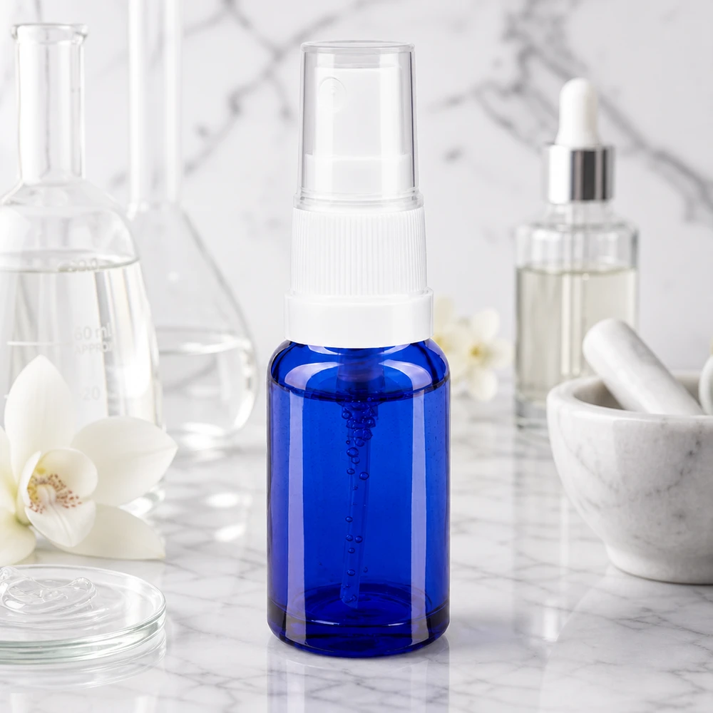 10 ml sprayflaske af blåt apotekerglas med hvid forstøver på marmorunderlag i laboratoriestil