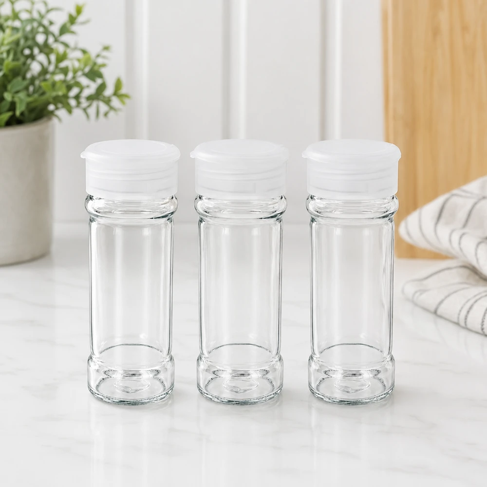 Salt-/krydderikrukke 100 ml med strøer, hvid Tre tomme krydderiglas i klart glas, 100 ml, med hvide strøhætter på en marmoroverflade