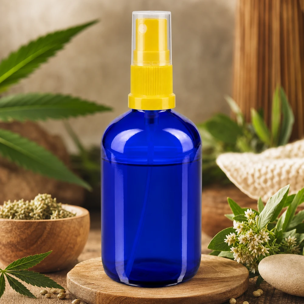 Blå 100 ml glasflaske med gul sprøjtehoved omgivet af hamp og naturlige urter