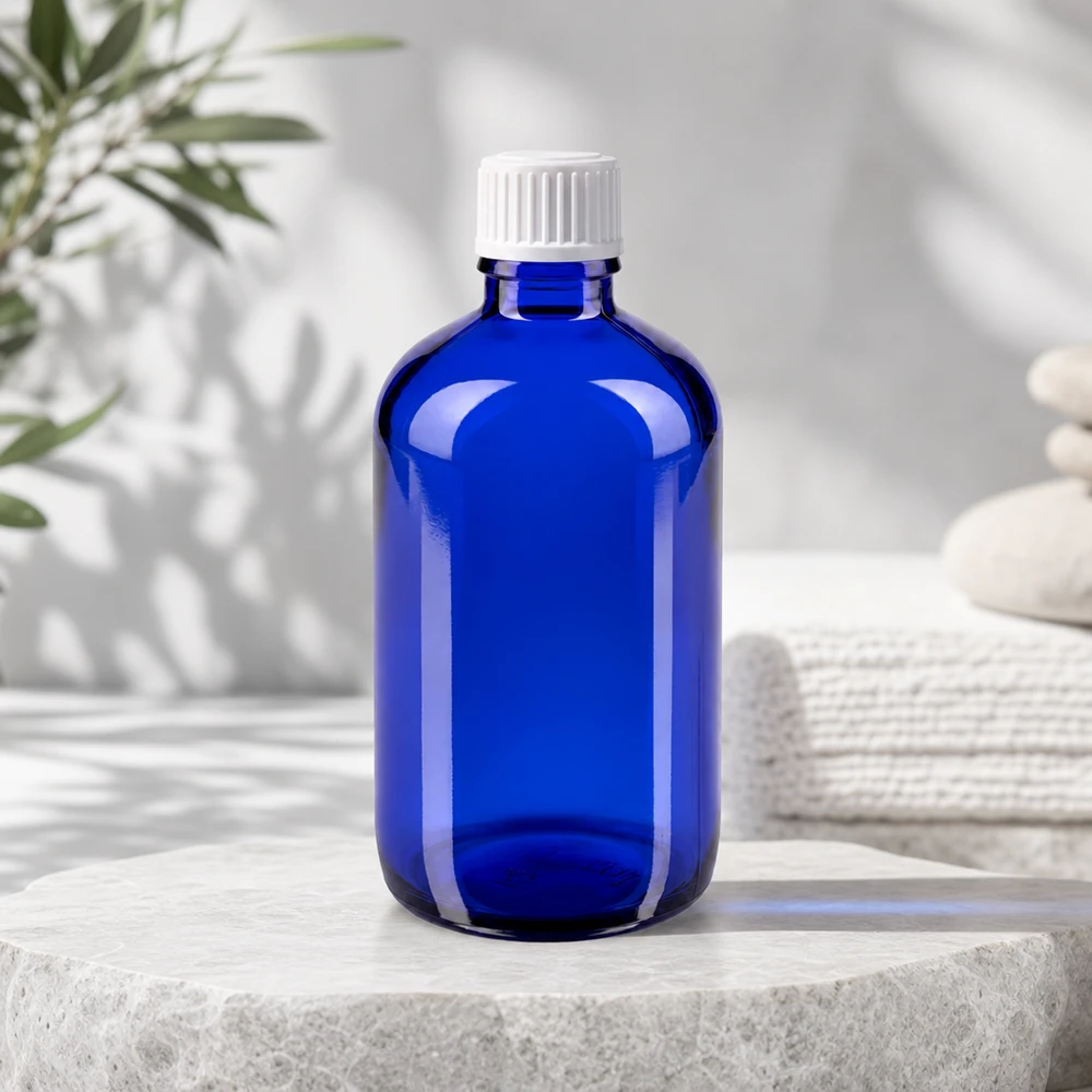 Apoteksflaske blå 100ml skruelåg hvide kugler St Blå apotekerglasflaske på 100 ml med UV-beskyttelse og hvid standardprop til æteriske olier
