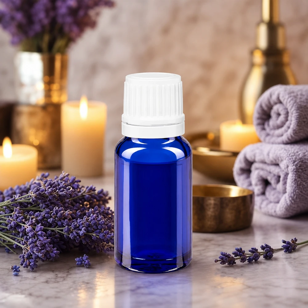 Blå 10 ml glasflaske med dråbeindsats omgivet af lavendelblomster og stearinlys