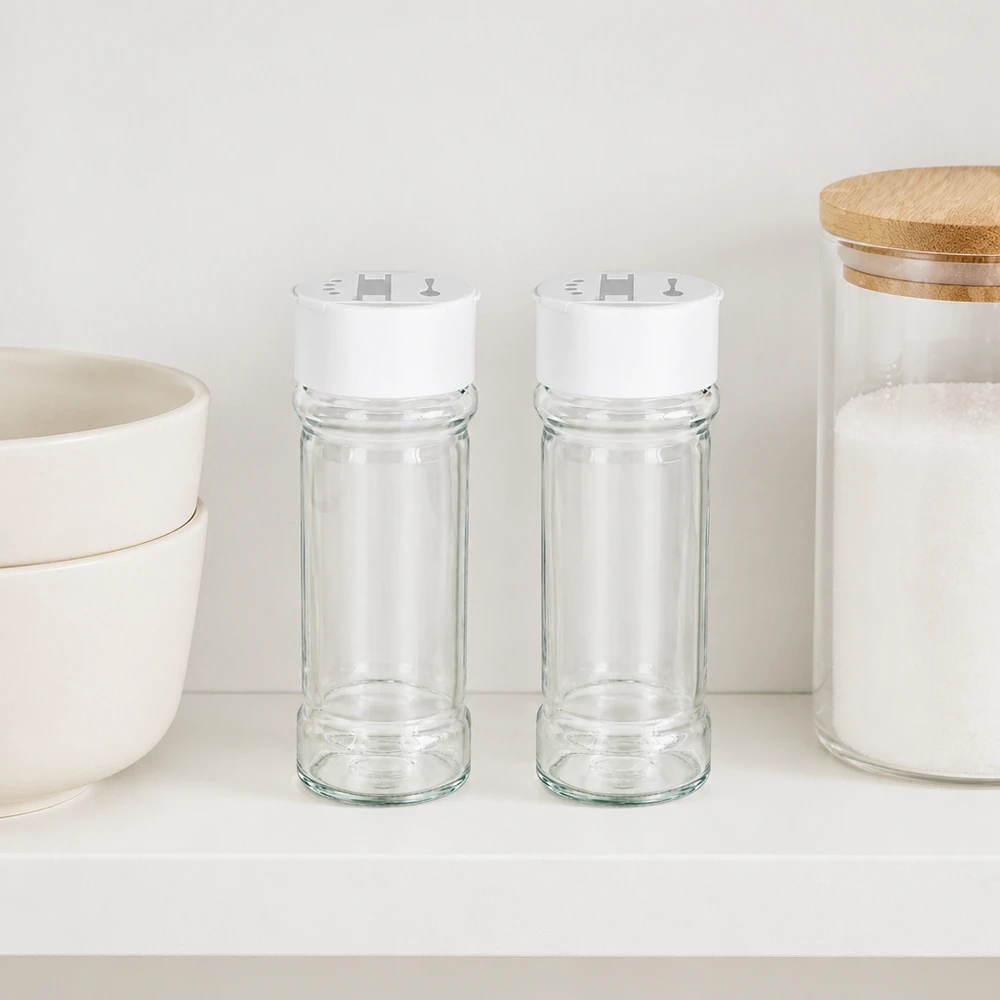 Salt-/krydderikrukke 100 ml med dobbelt strøer, hvid To krydderiglas på 100 ml med hvidt låg med dobbelt strøfunktion, der står side om side på en hvid hylde