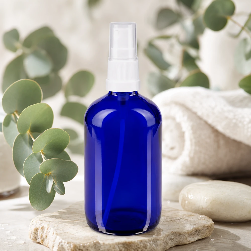 Rund 100 ml sprayflaske af blåt UV-beskyttende glas med hvid pumpespray på natursten