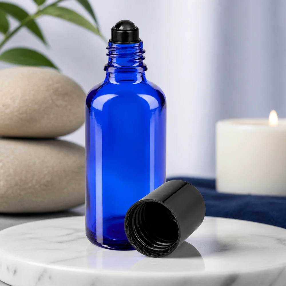 Blå 50 ml glasflaske med sort roll-on-applikator og fjernet låg på marmor
