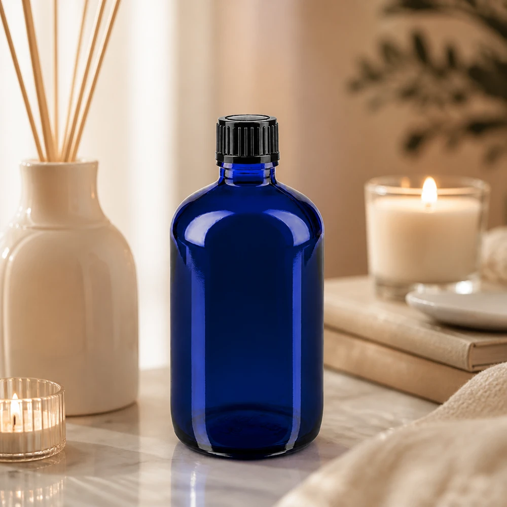Koboltblå apotekerflaske på 100 ml med sort dråbepropp på marmor