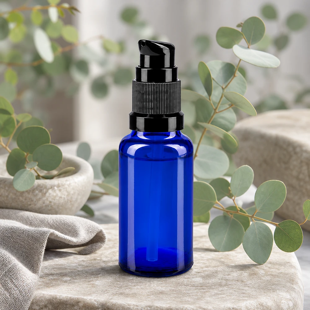 Blå 20 ml apotekerflaske med sort doseringspumpe foran eukalyptusgrene