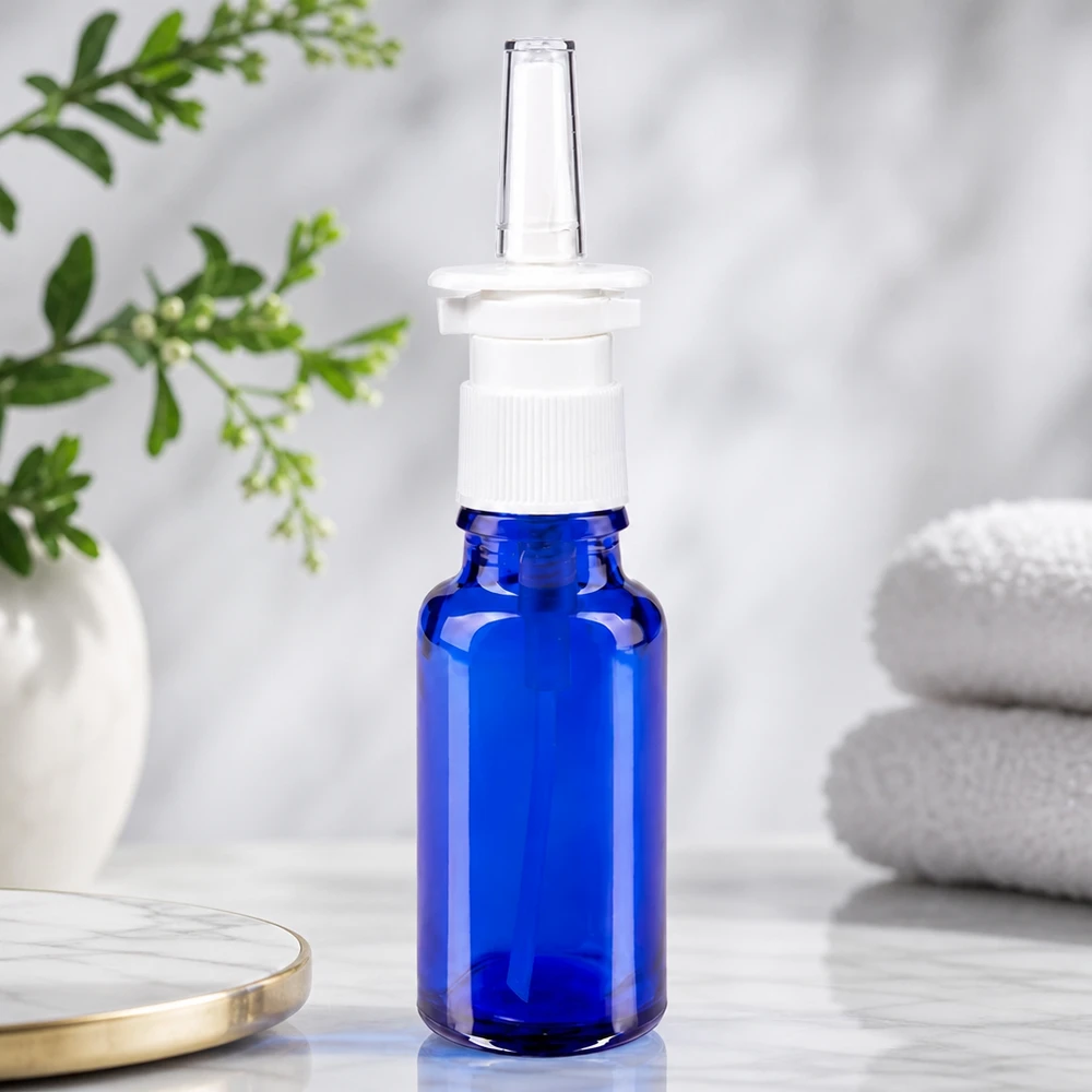 Apoteksflaske blå 20 ml næseforstøver hvid St Blå 20 ml apotekerflaske med gennemsigtig næsespraydyse og hvid trykhoved på marmor
