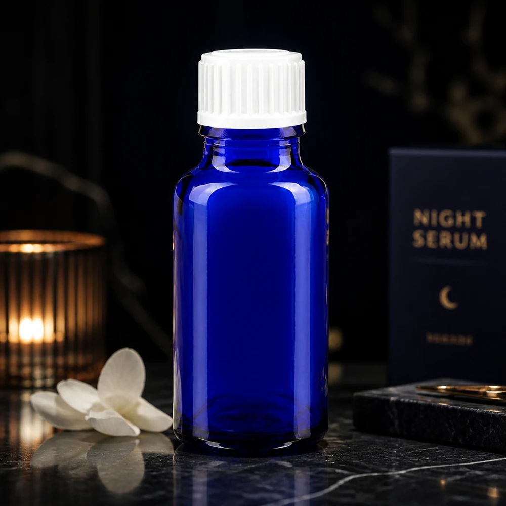 Koboltblå 20 ml glasflaske med hvid prop ved siden af Night Serum-emballagen på mørk baggrund