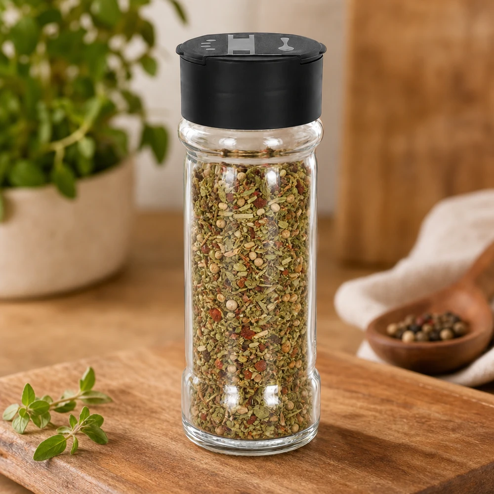 Salt-/krydderikrukke 100 ml med dobbelt strøer, sort Krydderiblanding i en 100 ml krydderikrukke af klart glas med sort dobbeltlåg på et træbræt