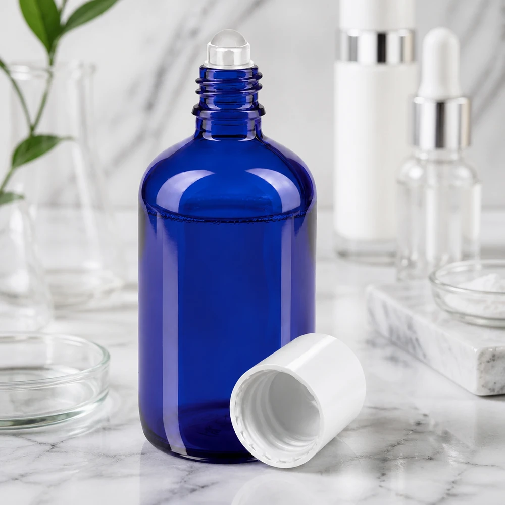 Blå 100 ml glasflaske med rullekugle og hvidt låg på marmoreffekt