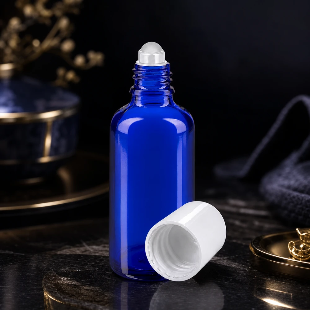 Apoteksflaske blå 50 ml roll-on-hætte hvid En åben, blå apotekerflaske på 50 ml med hvid rullekugle på en mørk marmoroverflade
