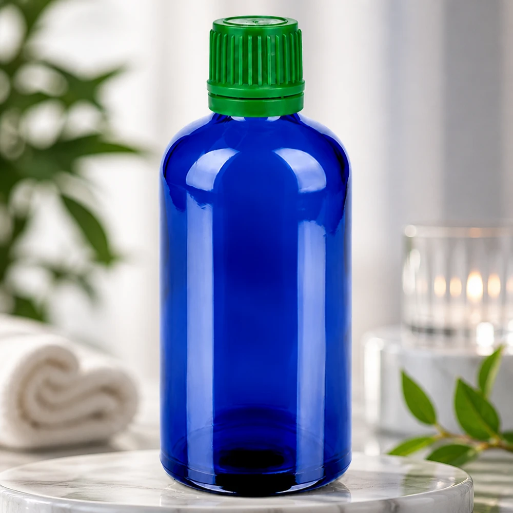Kompakt 100 ml glasflaske i blå med grøn hætte til præcis dosering og sikker opbevaring