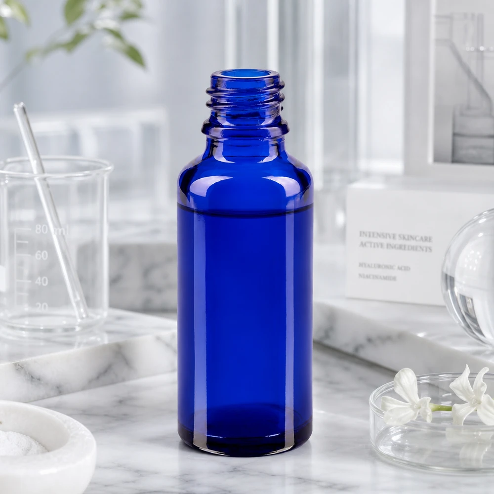 Koboltblå 30 ml ApoGlas-flaske i laboratoriemiljø med målebæger og ingredienser til hudpleje