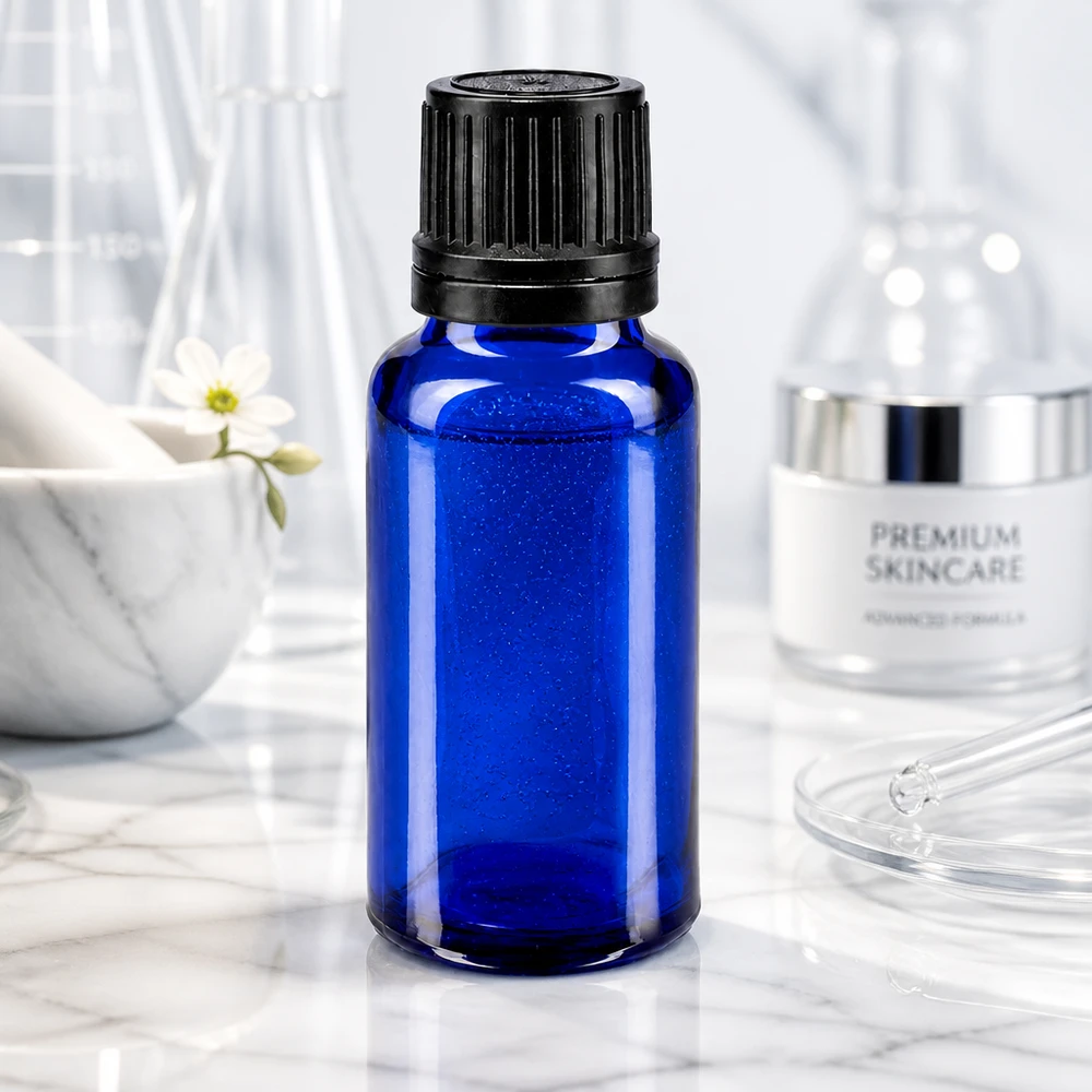 Blå 20 ml glasflaske med sort skruelåg foran laboratorieglas på marmorunderlag