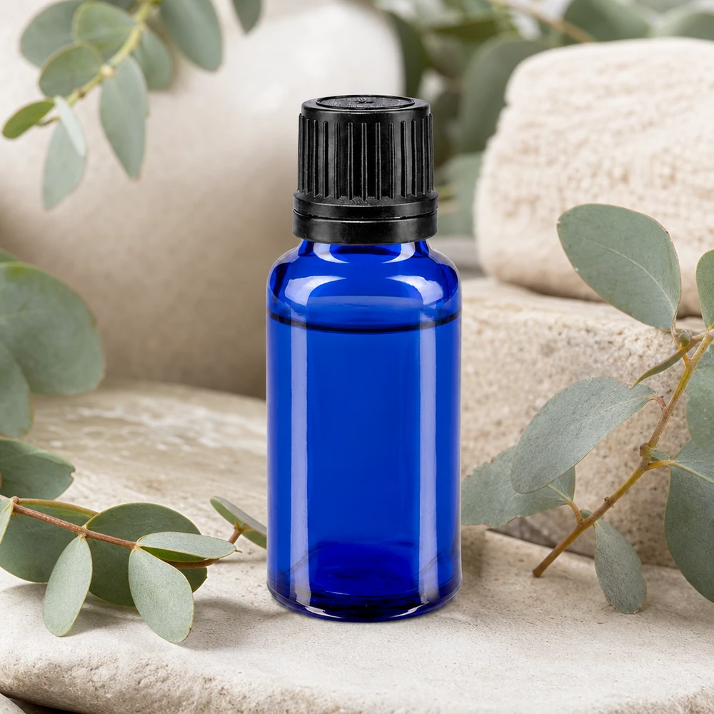 Koboltblå 20 ml apotekerflaske med 1 mm dråbeindsats mellem eukalyptusgrene på natursten