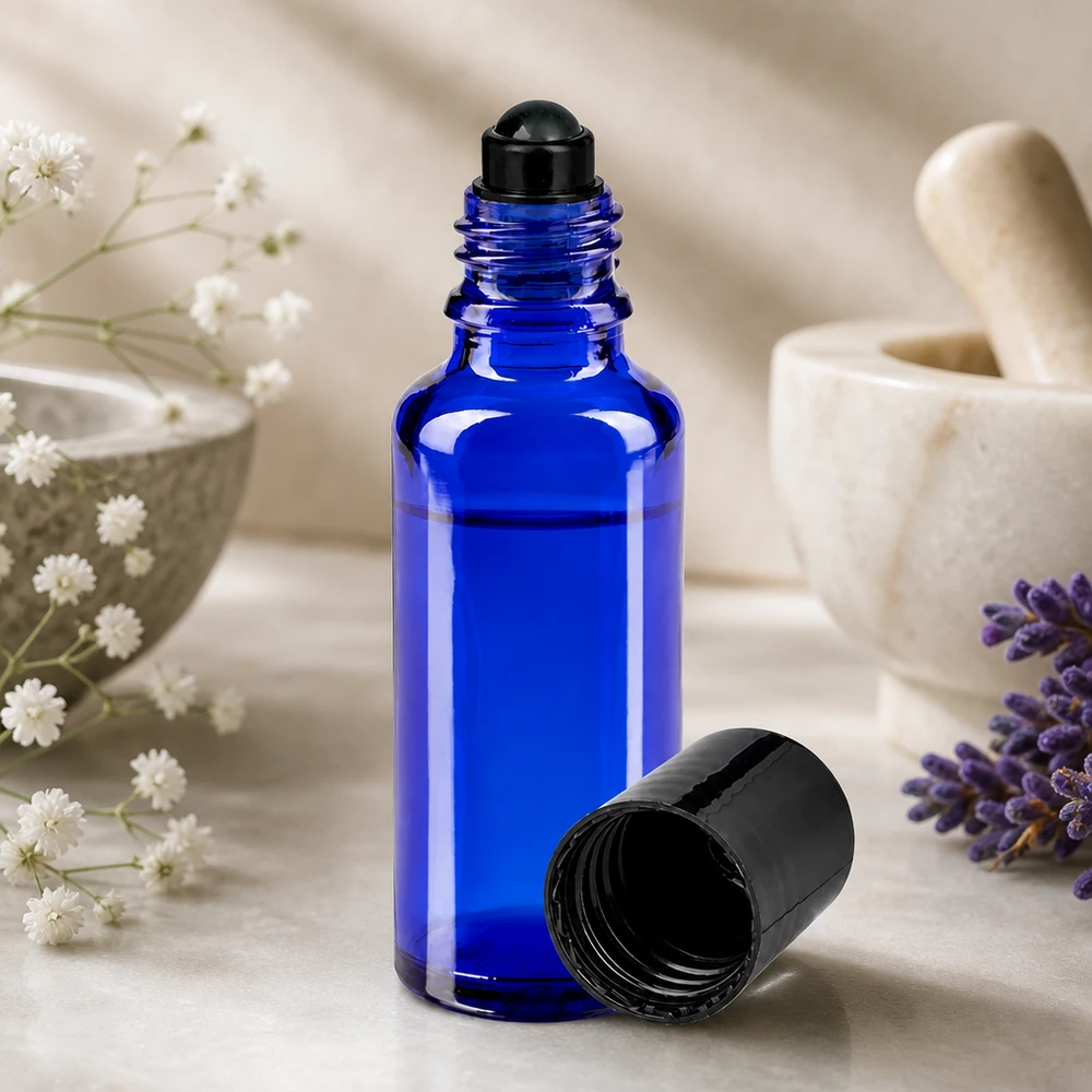 Blå 30 ml apoteker-roll-on-flaske med sort rullekugle ved siden af lavendel og morter
