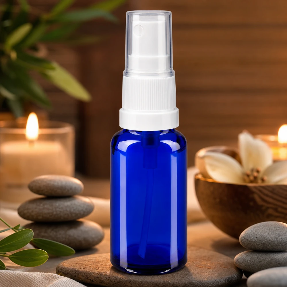 Apotekerflaske blå 20 ml spraytilbehør hvid Blå 20 ml apotekerflaske med sprayhoved i hvidt glas i en wellness-spa-atmosfære med stearinlys